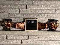 Wide view of the three-piece fireplace decor set arranged on stone shelf: two Egyptian urns with a central metal tin piece