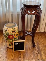 Photo showing full view of vintage floral ceramic floor vase and carved wooden occasional table with faux marble top on hardwood floor