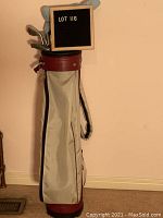 Full view of the ladies golf bag showing its beige and maroon color with carry strap and pocket