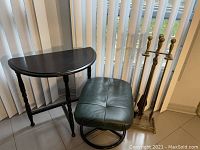 Living room lot showing green leather ottoman, black half moon table and brass fireplace accessories