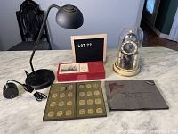 Full lot including vintage desk lamp, Olympic medallion set in case, antique photo album, and vintage clock under glass dome.