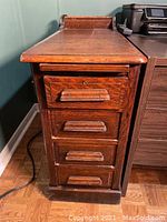 Front and side view of the oak filing cabinet showing four drawers and wooden pulls.