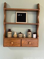 Full view of oak shelf with two drawers and various ceramic jugs placed on the bottom shelf, showing labels on some jugs and overall condition.