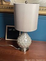 Full view of mid century modern table lamp on wooden surface with fabric lampshade and bubbled glass base.