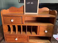 Front view of vintage wooden cubby organizer with white knobs and multiple compartments.