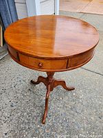 Full view of the wooden round antique drum table with pedestal and three legs, showing overall shape and structure.