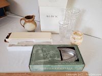 Photo showing entire lot including silver plate cake serving set, two crystal vases, pottery vase, alabaster vase, Wilton Armetale platter in box, and packaging