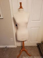 Front view of dressmaker's form showing cloth cover and wooden top piece.