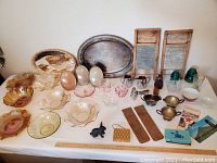 Full display of all glassware, silverplate items, washboards, and ephemera on a white tablecloth showing lot contents