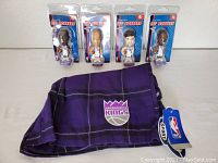 Four unopened Sacramento Kings Lil' Bobbers bobbleheads and one pair of purple Sacramento Kings boxers with tags showing team logo