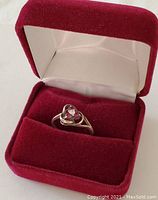 Ring inside a red velvet ring box showing the overall item and protection box.