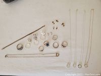 Top-down view of all jewelry laid out on a white surface including rings, earrings, bracelets, and necklaces with pendants.
