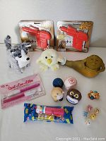 Wide angle photo showing all toys in the lot including the two water guns, plush animals, Jabba the Hutt figure, baseball, novelty pen, PEZ dispenser, and small figurines.
