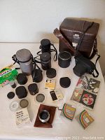 Wide shot showing film camera, multiple lenses, leather cases, and accessories including Fujifilm film