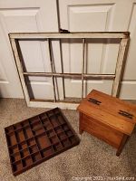 Antique window frame, printers tray and storage stool arranged on carpeted floor against white doors