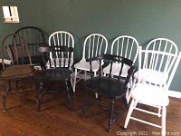 View of the eight chairs including white painted chairs, black armchairs, and a natural wood cane seat chair.