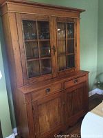 Front view of two-tier country cabinet showing glass upper doors, drawers and lower paneled doors