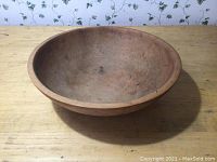 Angled side view showing bowl shape, wood grain, and wear marks on the surface.