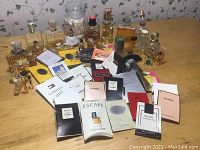 Photo showing a large assortment of perfume bottles, sample vials, and branded perfume sample cards arranged on a table.