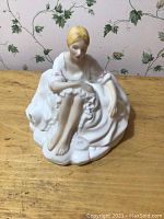 Front view of Royal Doulton Joanne figurine showing seated woman with blonde hair, white dress, barefoot.