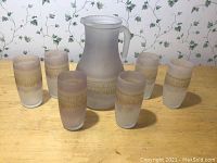 Full set including frosted glass pitcher and six matching glasses on wooden surface, showing overall condition and design.