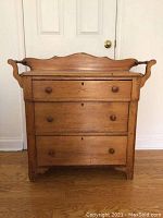 Front view of washstand showing three drawers, wooden knobs and shaped gallery back