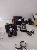 Wide view of all items on table: binoculars, flashlight, stereo cassette player, camera, and mobile phone.