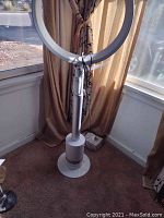 Full view of Dyson Cool bladeless fan standing tall near window with curtain background.