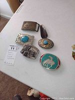 All belt buckles and shoe horn displayed on table, showing overall lot contents and condition