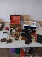 Wide view of all items including watches, wallets, coin bags, cufflinks, and the skin care box on the table