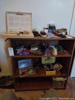 Full view of wooden shelf with various tools, miniature trains, model cars, belts and personal care items arranged on shelves and top surface.
