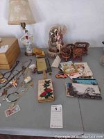 Wide view of the items on display including postcards, miniature wicker furniture, porcelain figurines, jewelry, and vintage compact