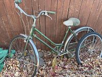 Full side view of green vintage Schwinn girl's bike showing frame, wheels, handlebars, and seat.