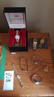 Overview of six watches on tabletop, including boxed Seiko and assorted gold- and silver-tone watches