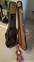 Open case showing violin inside with bow and candy tin on floor
