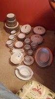 Overview of entire china set arranged on carpet, showing plates, cups, saucers, lidded dishes and gravy boats