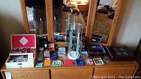 Wide view of dresser top showing an assortment of jewelry boxes, stand, and loose items arranged neatly.
