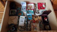 Overall view of assorted costume jewelry displayed in boxes showing bracelets, necklaces, brooches, pins, and rings.