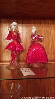 Full view of two glass flamenco dancer figurines on a shelf, male dancer on left and female on right