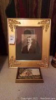 Framed vintage black and white portrait photo of a man, and framed oil painting sitting on floor