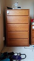 Front view of tall wooden dresser with 5 drawers, clean wood finish, recessed handles.