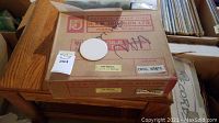 Box labeled H.R. Johnson Ltd. containing opal white tiles, showing one round sample tile on top.