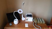 Overview of all items on wood desk showing lamps, picture frame, alarm clock and phone
