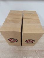 Four brown cardboard boxes arranged side by side with Adams logo for shipping or storage of glass cleaner bottles.