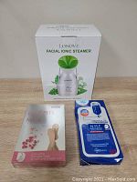 Front view of the LONOVE Facial Ionic Steamer box alongside the Mediheal NMF Aquaring Ampoule Facial Mask and ACANI Foot Peel Mask box.