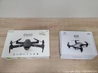 Both Eachine E520 and Deerc D20 drones in original boxes side by side on wooden surface.