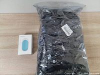 Black heated vest in original plastic packaging with size XL label visible, and white box of hand warmer beside it.