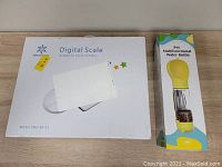 White box for the digital scale labeled Model: SNO-BS-01 paired with a colorful boxed pet multifunctional water bottle with a yellow top and treat storage compartment.