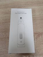 White boxed professional pet nail grinder shown on wooden floor.