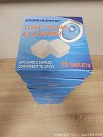 Stack of 12 identical blue boxes of SEGMINI Smart Toilet Bowl Cleaner, each box marked with 15 tablets.